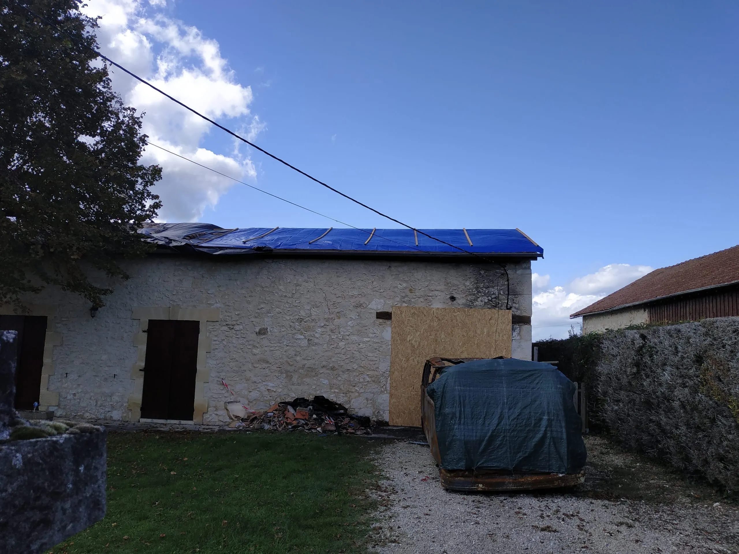 Protection provisoire d’une toiture par une grande bâche bleue