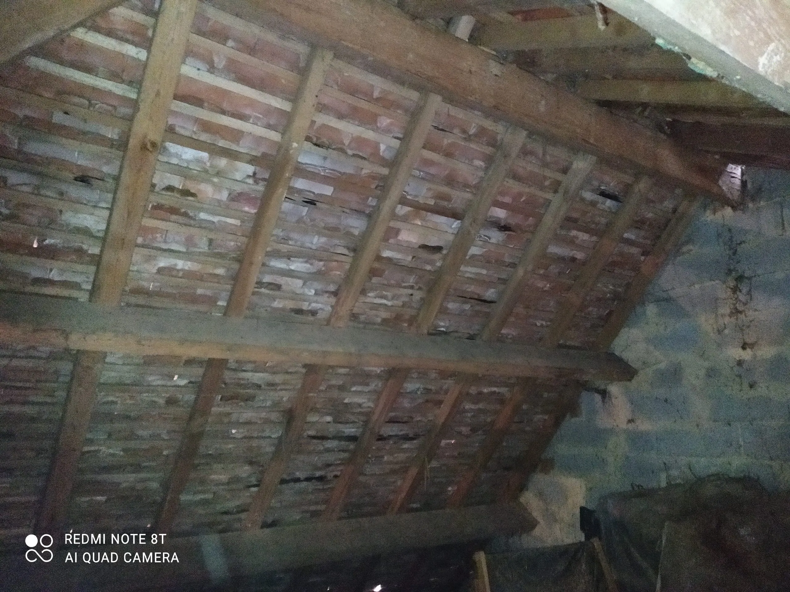 Charpente ancienne en bois et tuiles en terre cuite vues depuis l’intérieur des combles