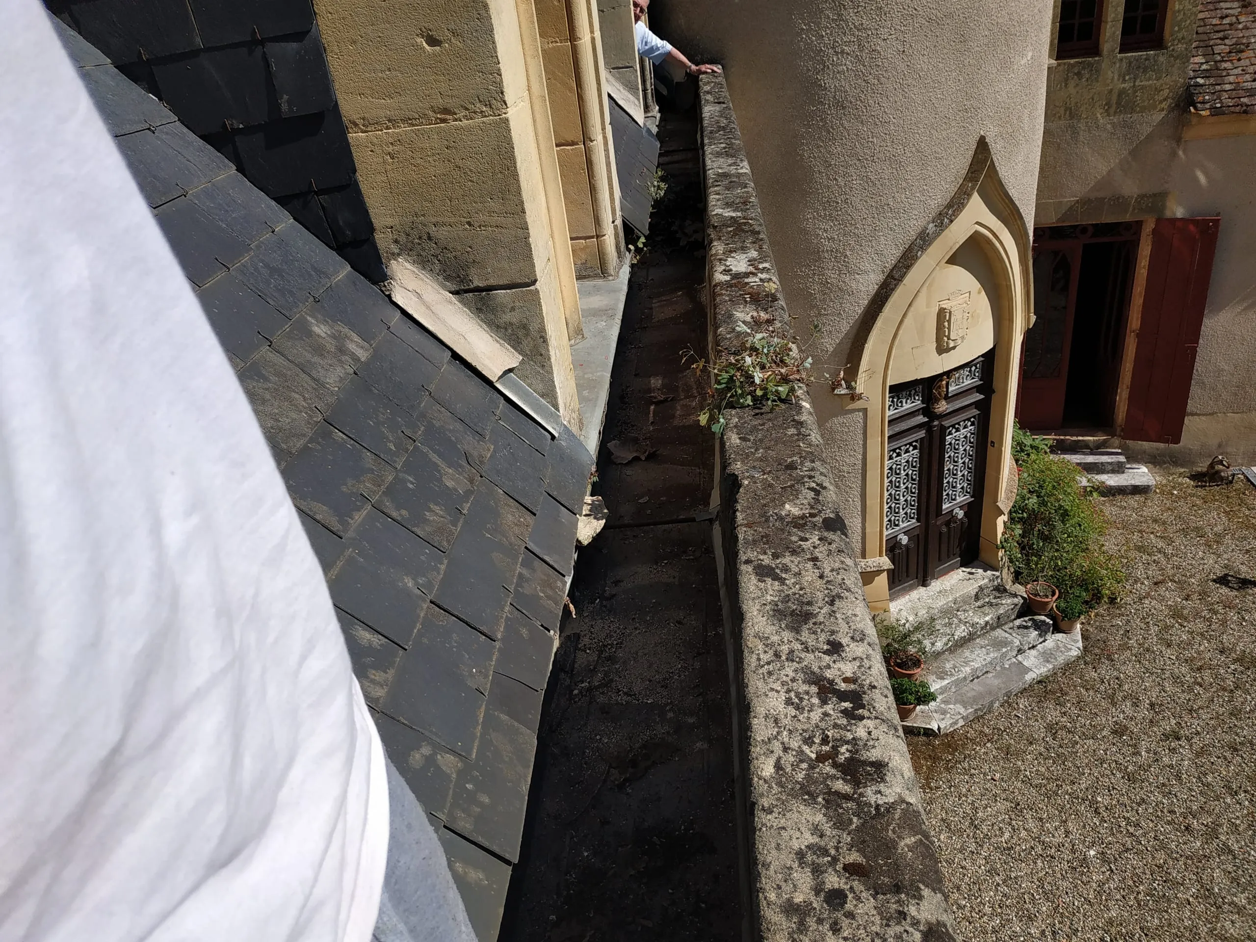 Inspection d’une toiture en ardoise et de ses raccords contre un bâtiment ancien en pierre