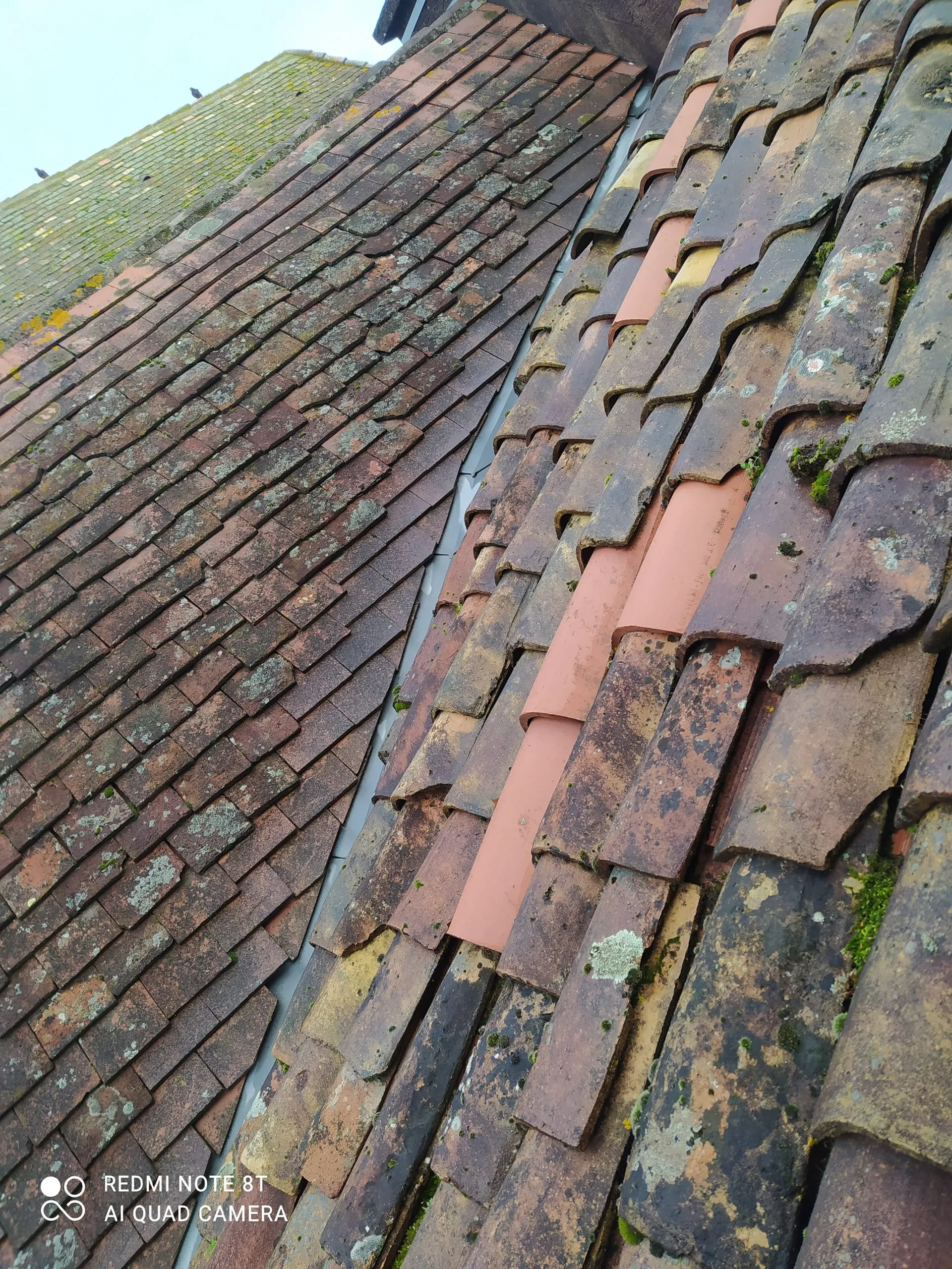 Détail d’une jonction en zinc entre deux pans de toiture en tuiles anciennes