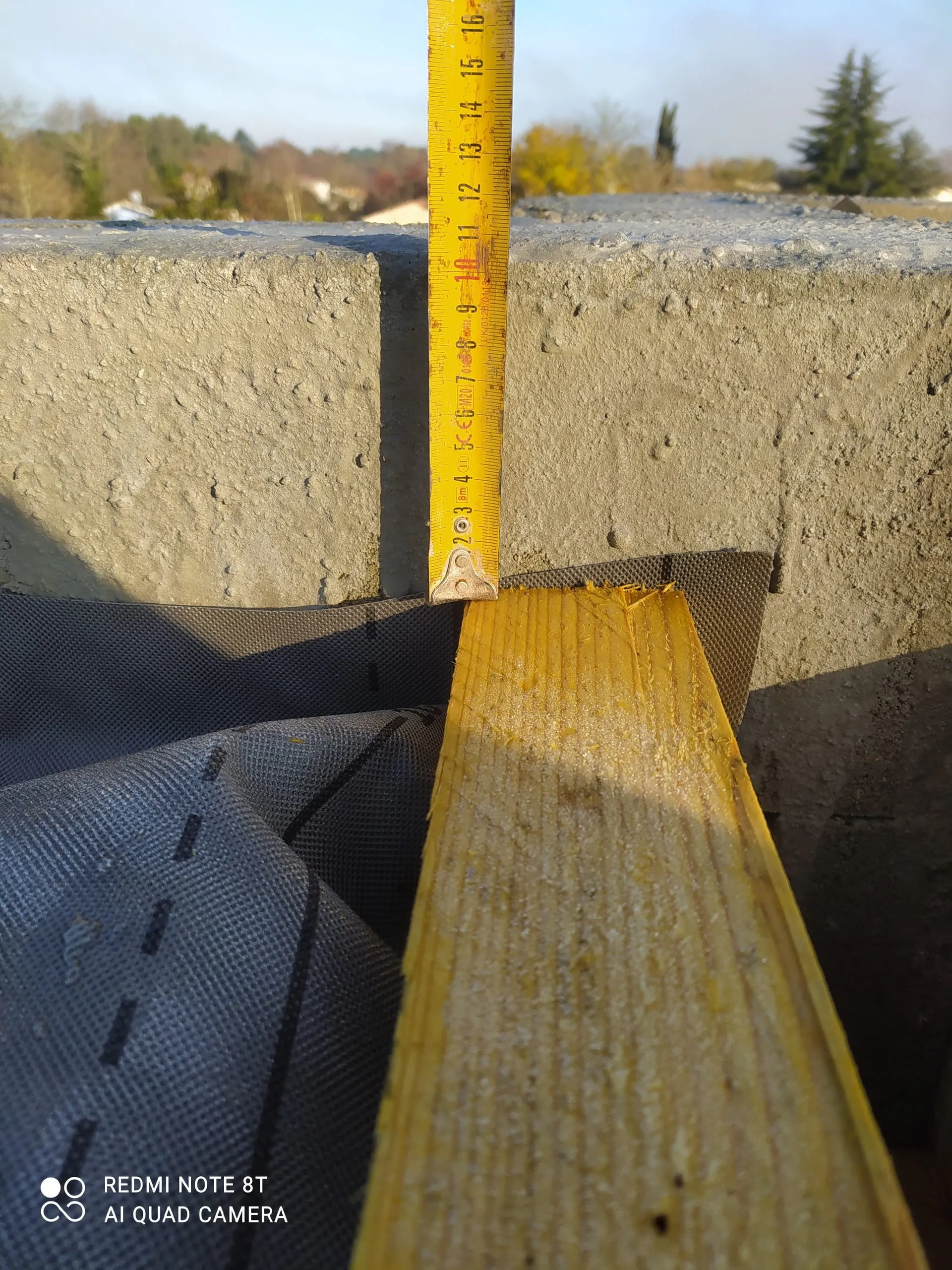Mètre ruban posé sur une couche d’isolant jaune au bord d’une toiture