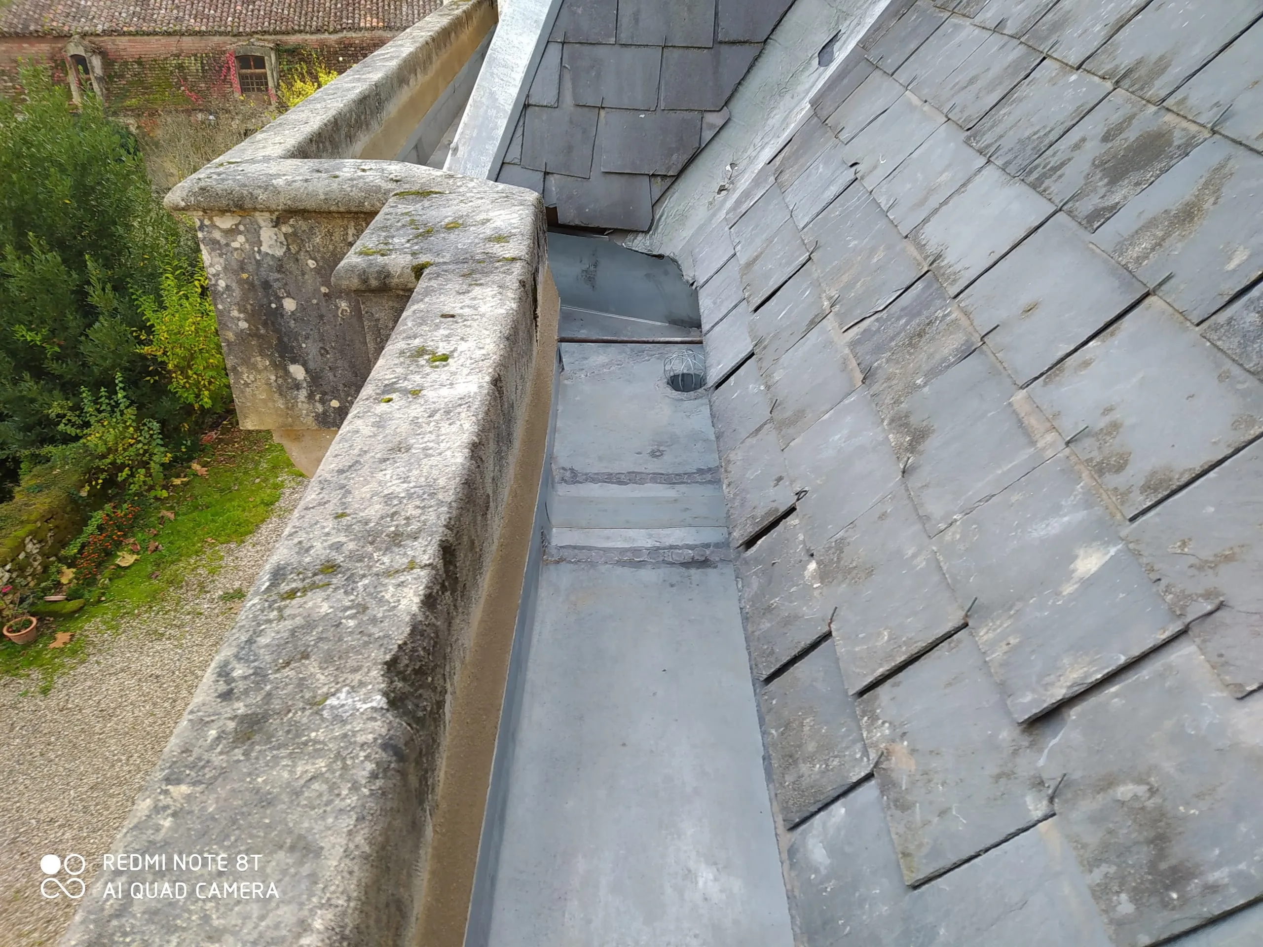 Raccord en zinc le long d’un parapet en pierre et d’une toiture en ardoise