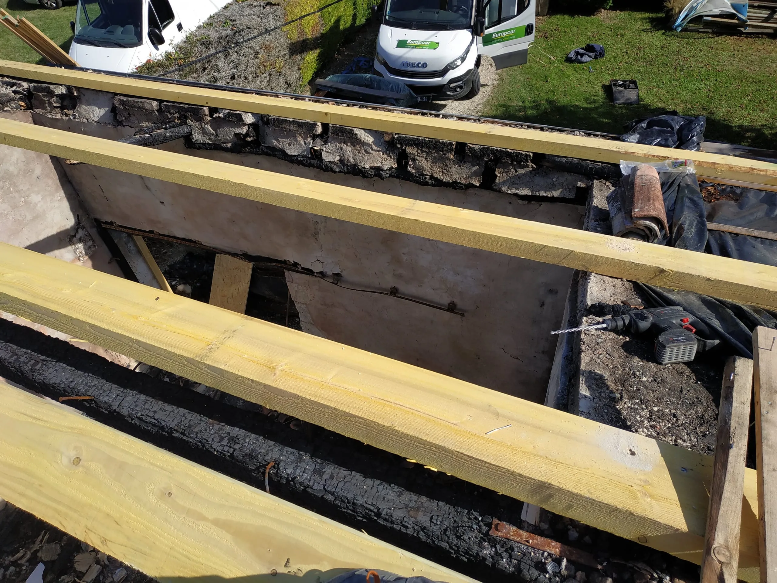 Pièces de bois neuves posées au-dessus d’une maçonnerie ancienne lors d’une rénovation de charpente