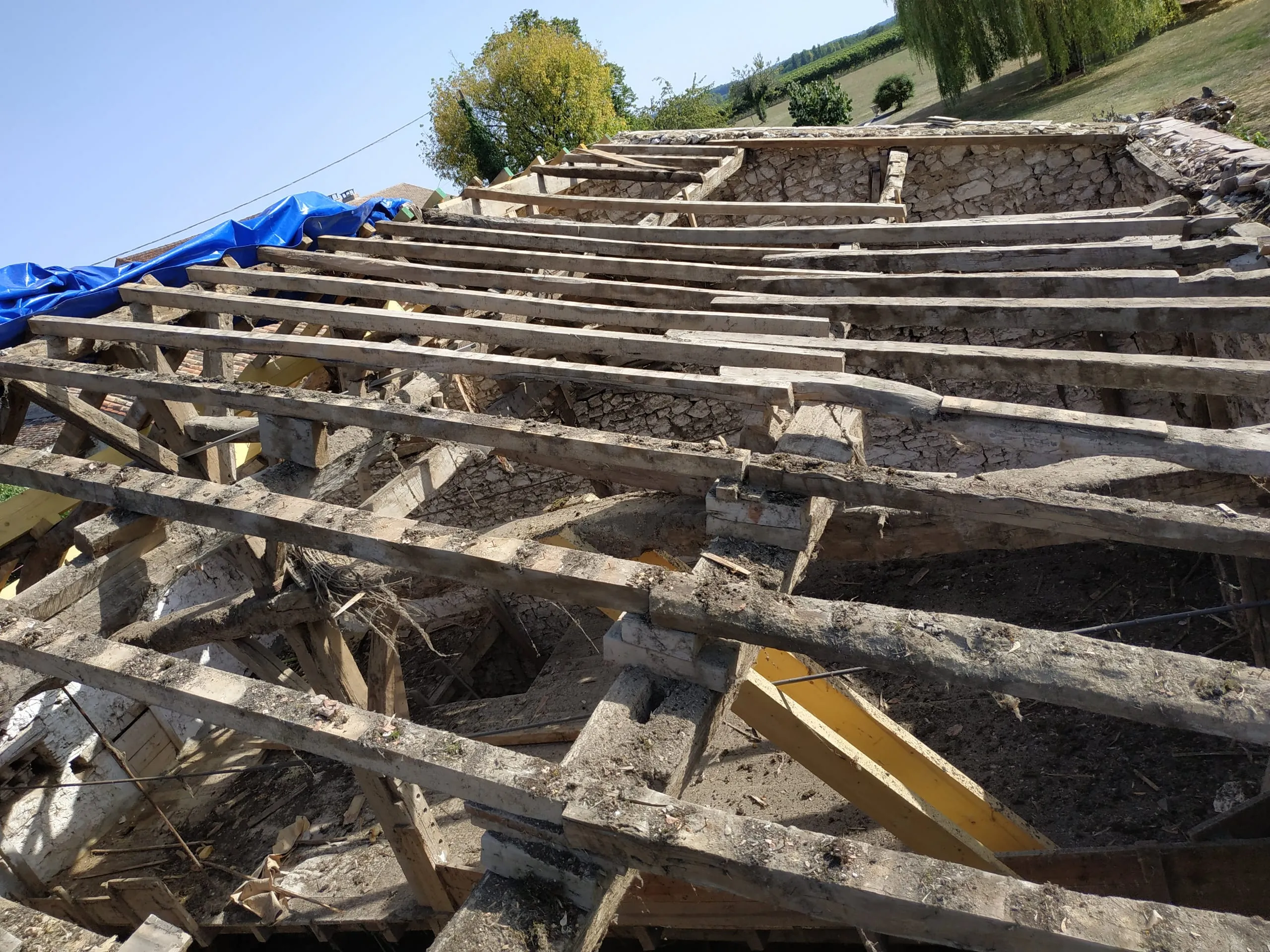 Charpente ancienne mise à nu sous une toiture partiellement déposée