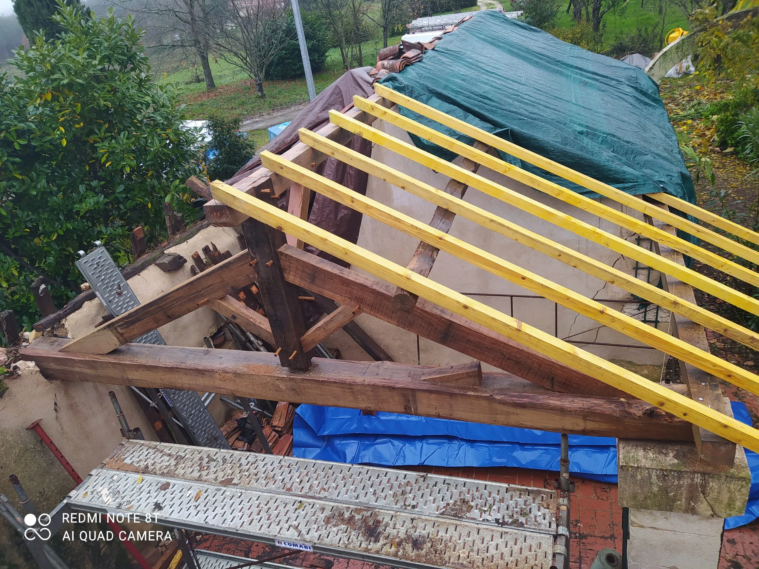 Toiture en rénovation avec charpente ancienne apparente, liteaux neufs et bâche de protection