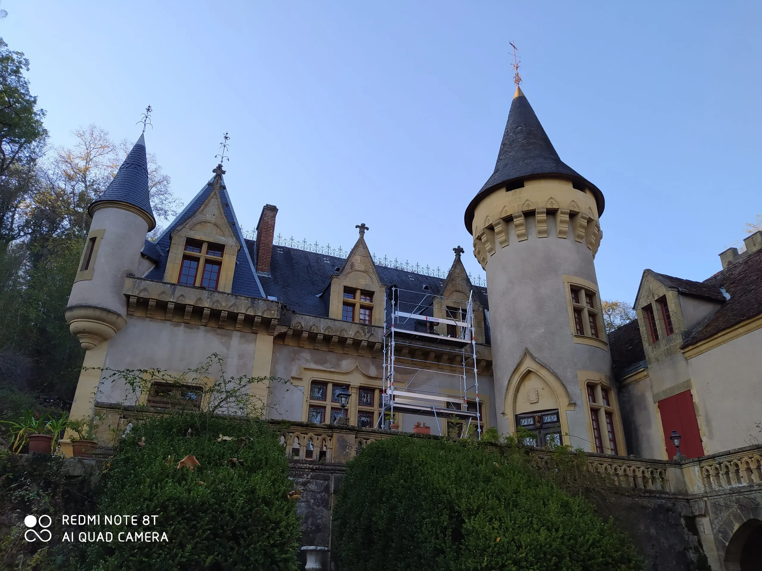 Longue toiture en tuiles en cours de rénovation sur une maison en pierre entourée d’un échafaudage
