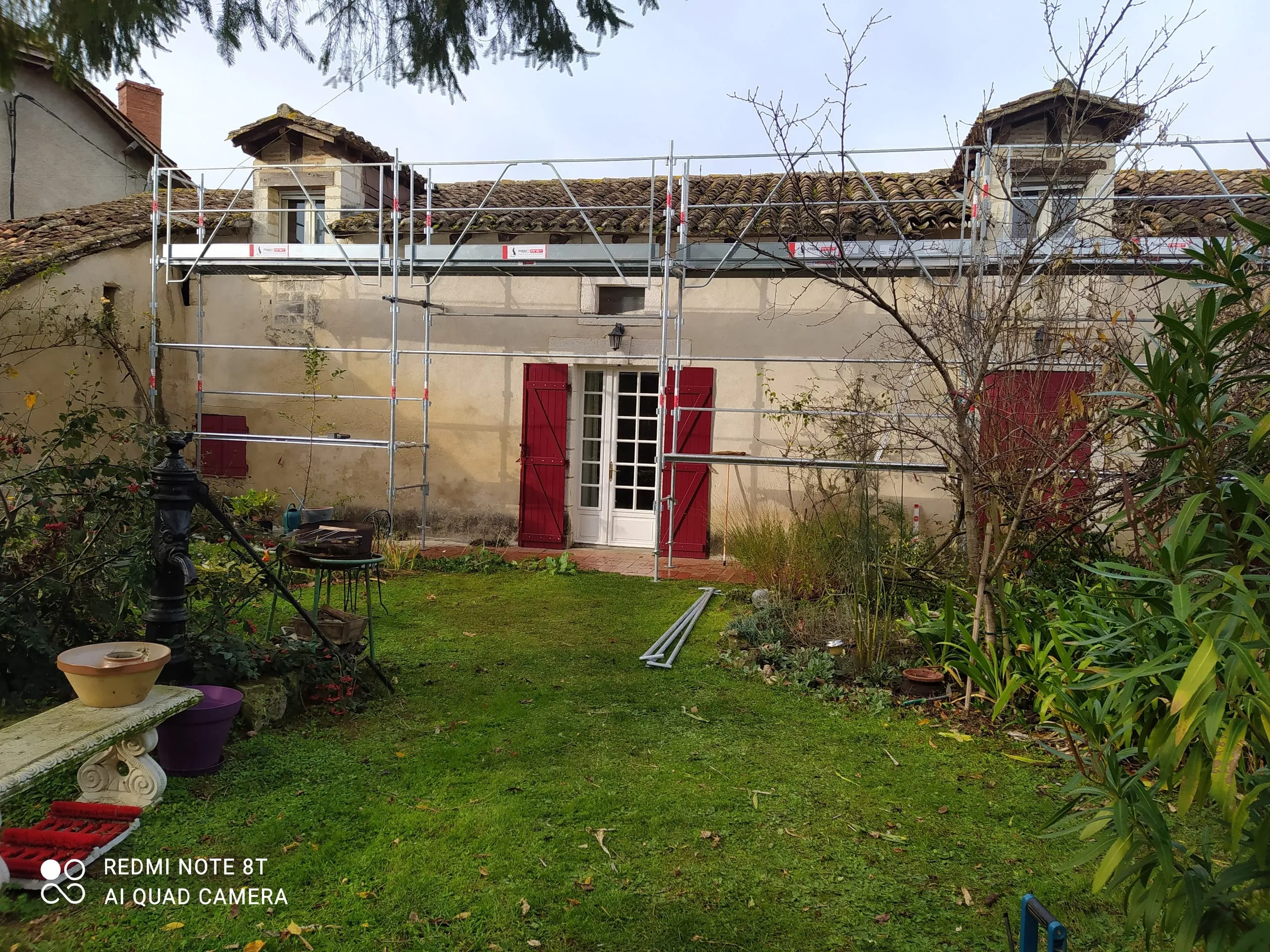 Maison ancienne entourée d’un échafaudage pendant la rénovation de sa toiture en tuiles