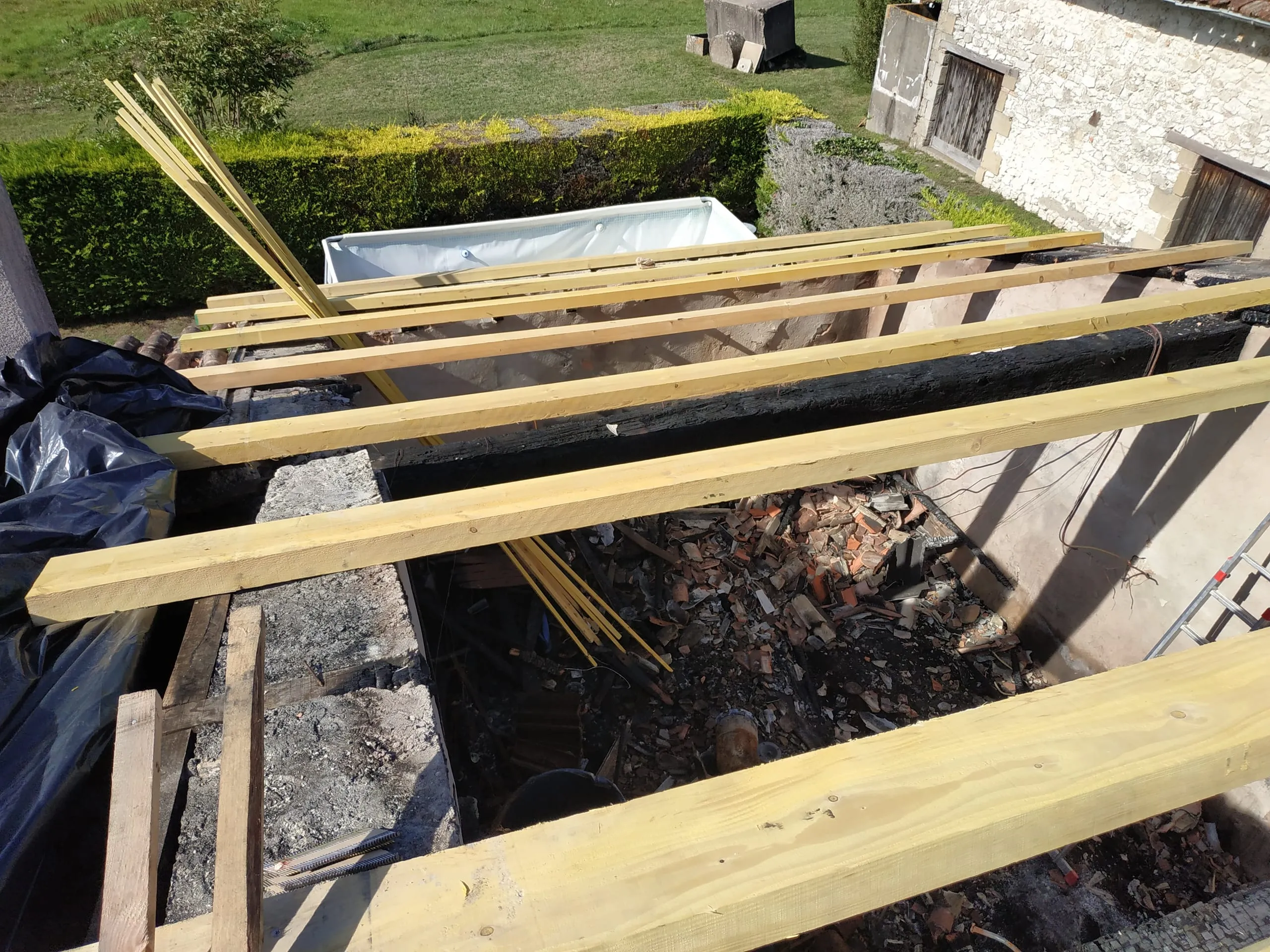 Pièces de bois neuves posées au-dessus d’une maçonnerie et de bois anciens