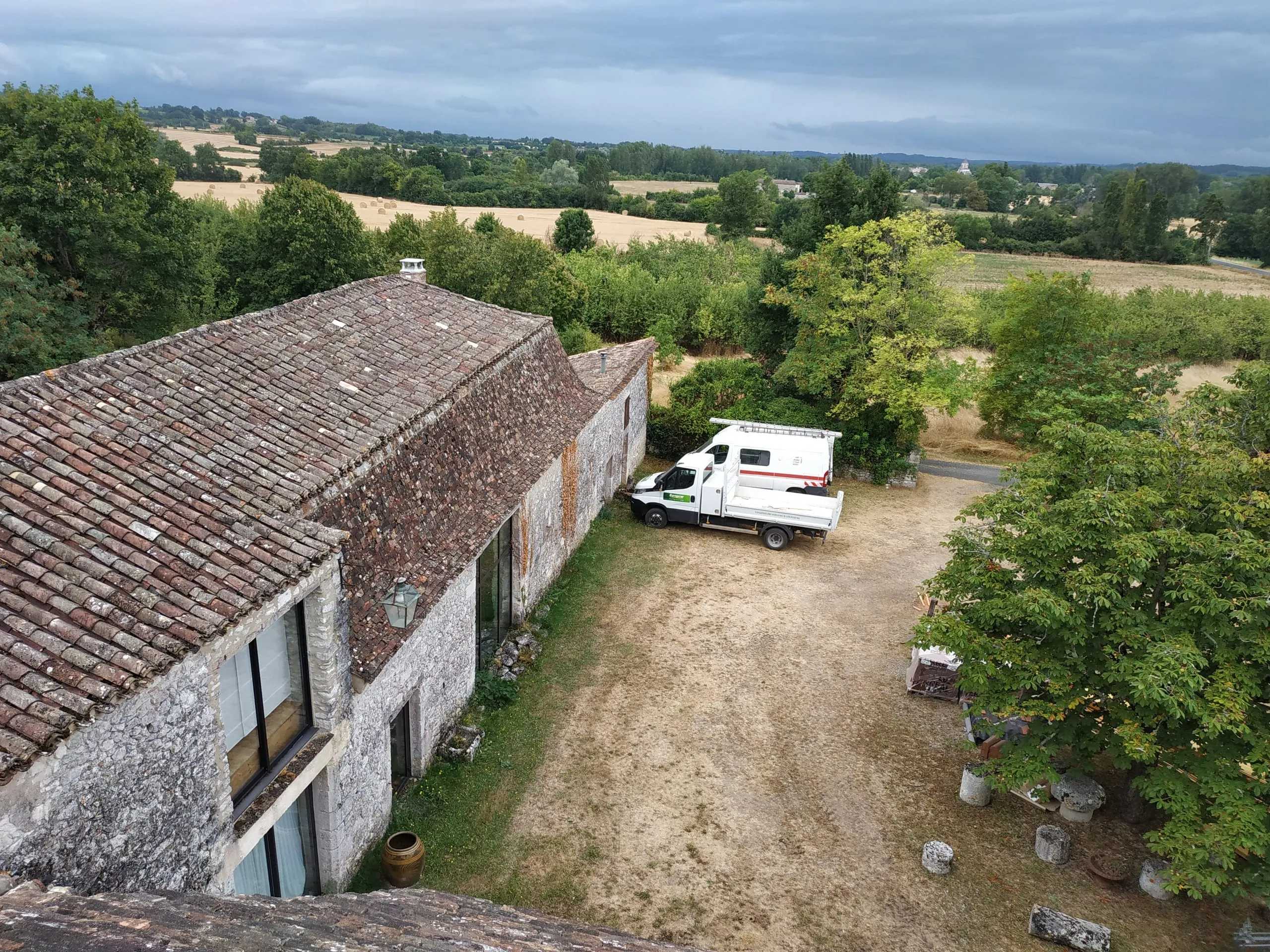 Ancienne toiture en tuiles sur une bâtisse en pierre dans un paysage rural