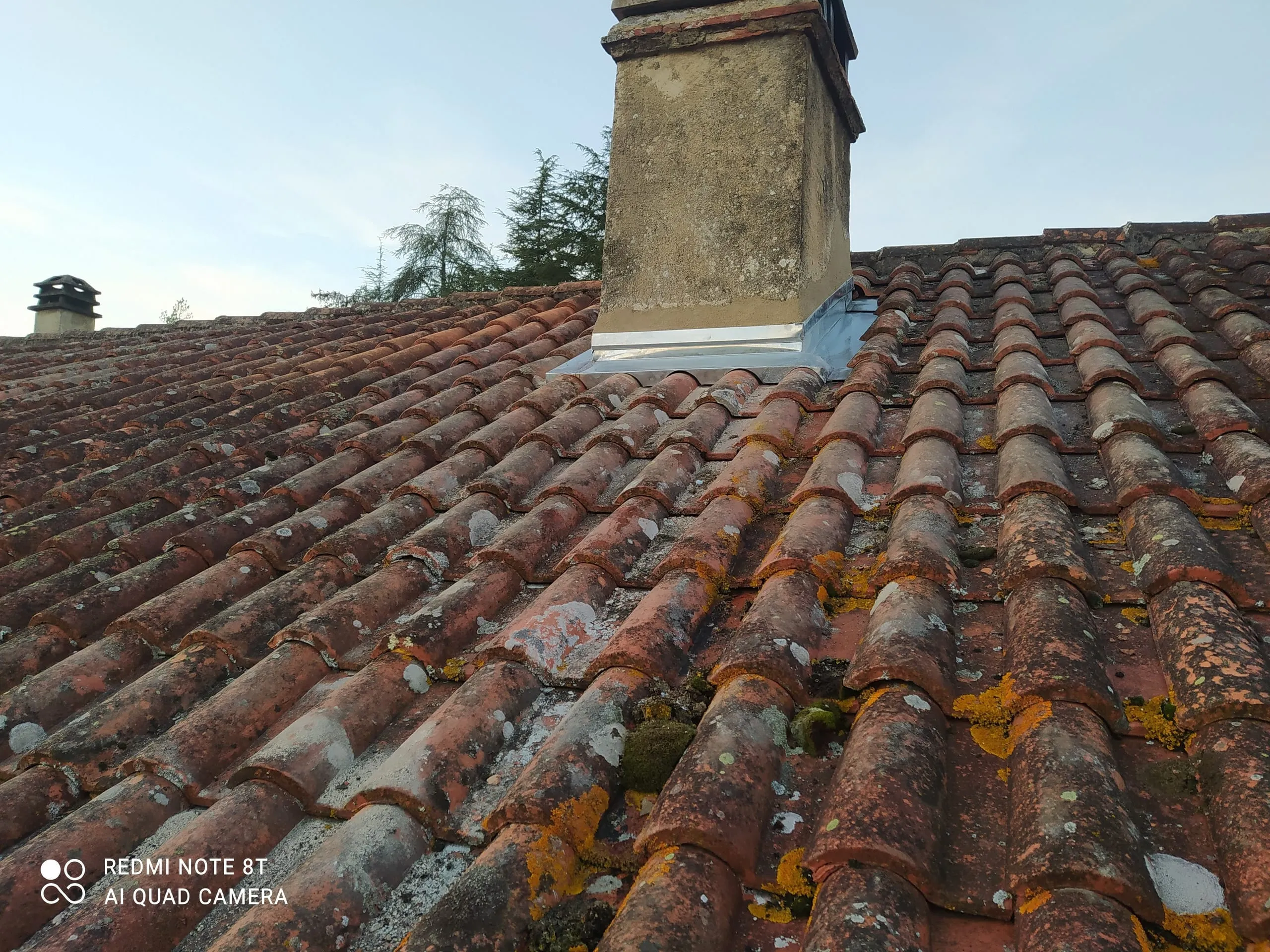 Toiture en tuiles anciennes avec mousse, lichens, cheminée et raccord en zinc